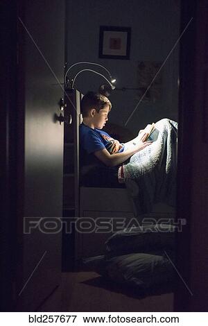 Caucasian boy reading book in bed at night View Large Photo Image Stock Photo - Caucasian boy reading book in bed at night. Fotosearch