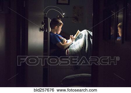 Caucasian boy reading book in bed at night View Large Photo Image Stock Photograph - Caucasian boy reading book in bed at night. Fotosearch