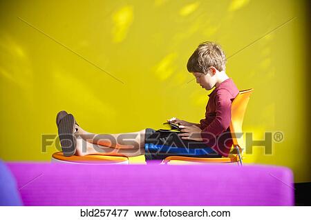 Stock Photo - Caucasian boy relaxing and reading digital tablet. Fotosearch