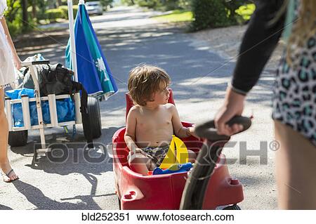 Caucasian boy riding in red wagon View Large Photo Image Stock Image - Caucasian boy riding in red wagon. Fotosearch