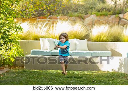 Stock Photograph - Caucasian boy running in backyard. Fotosearch