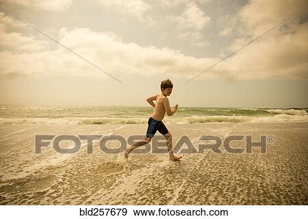 Caucasian boy running in ocean waves View Large Photo Image Stock Photo - Caucasian boy running in ocean waves. Fotosearch