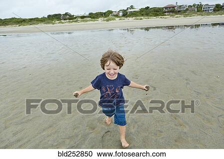 Caucasian boy running on beach carrying sand View Large Photo Image Stock Image - Caucasian boy running on beach carrying sand. Fotosearch
