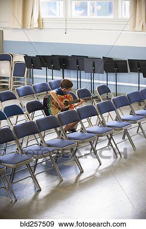 Caucasian boy sitting in row of chairs 1acticing guitar View Large Photo Image Stock Photo - Caucasian boy sitting in row of chairs 1acticing guitar. Fotosearch