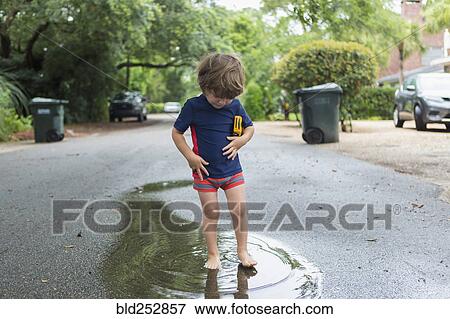 Caucasian boy standing in puddle on street View Large Photo Image Stock Photo - Caucasian boy standing in puddle on street. Fotosearch