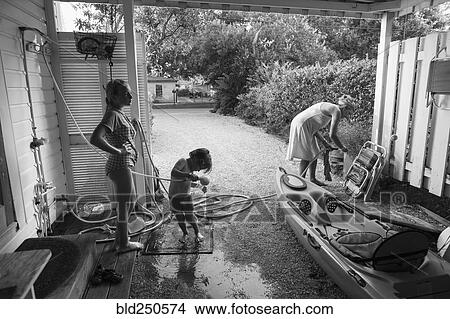 Caucasian boy using shower outdoors near mother and sister View Large Photo Image Picture - Caucasian boy using shower outdoors near mother and sister. Fotosearch
