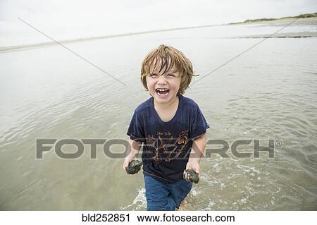 Caucasian boy waiting in ocean carrying sand View Large Photo Image Stock Image - Caucasian boy waiting in ocean carrying sand. Fotosearch