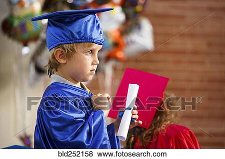 Caucasian boy wearing graduation robe holding diploma View Large Photo Image Stock Photo - Caucasian boy wearing graduation robe holding diploma. Fotosearch