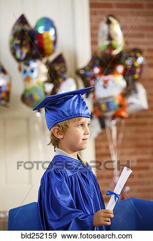 Caucasian boy wearing graduation robe holding diploma View Large Photo Image Stock Photo - Caucasian boy wearing graduation robe holding diploma. Fotosearch