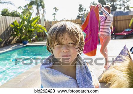 Stock Image - Caucasian boy wrapped in towel near swimming pool. Fotosearch