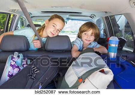 Stock Photo - Caucasian brother and sister in car with luggage. Fotosearch