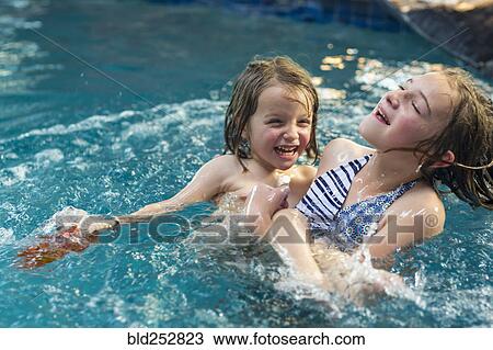 Stock Image - Caucasian brother and sister playing in swimming pool. Fotosearch