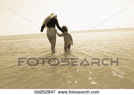 Stock Photo - Caucasian brother and sister wading in ocean. Fotosearch