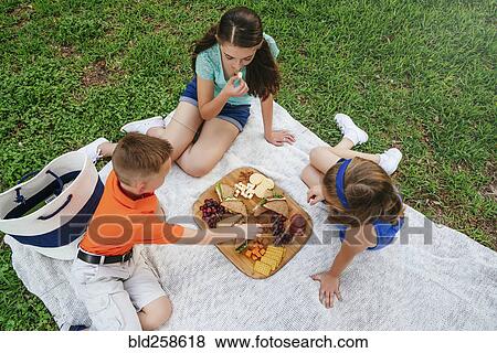 Caucasian brother and sisters eating snacks on picnic blanket View Large Photo Image Stock Photo - Caucasian brother and sisters eating snacks on picnic blanket. Fotosearch