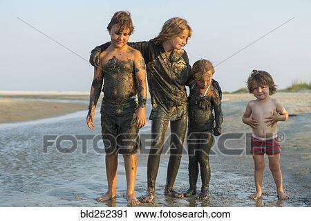 Caucasian brothers and sisters covered in mud standing on beach View Large Photo Image Stock Image - Caucasian brothers and sisters covered in mud standing on beach. Fotosearch