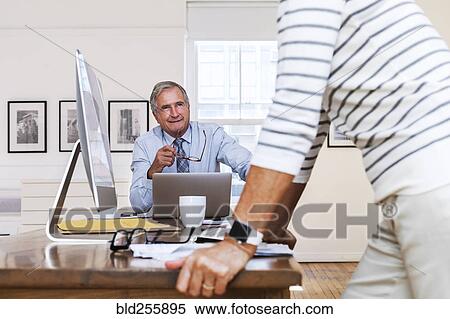 Stock Photography - Caucasian businessman and businesswoman talking at table. Fotosearch