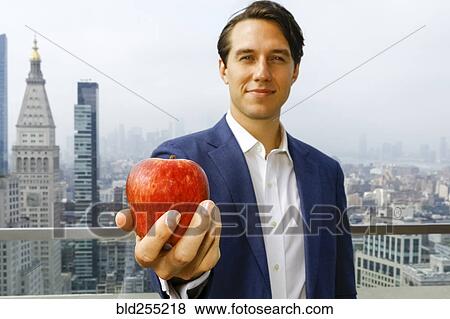 Caucasian businessman showing apple on urban rooftop View Large Photo Image Stock Photo - Caucasian businessman showing apple on urban rooftop. Fotosearch