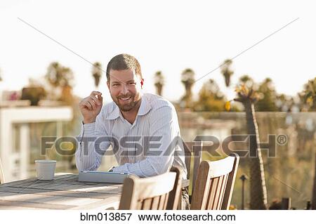 Stock Photo - Caucasian businessman taking break on patio. Fotosearch