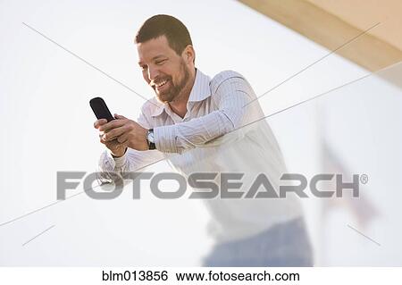 Stock Photograph - Caucasian businessman text messaging on cell phone. Fotosearch