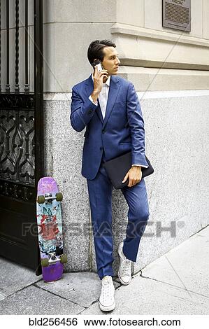 Stock Photograph - Caucasian businessman with skateboard talking on cell phone. Fotosearch
