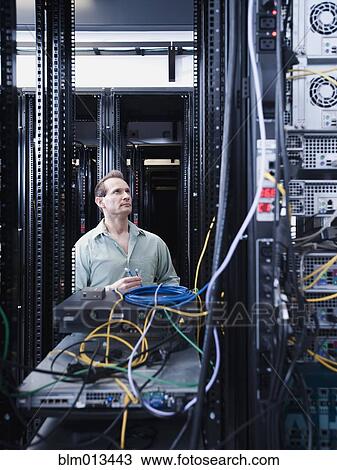 Stock Image - Caucasian businessman working in server room. Fotosearch