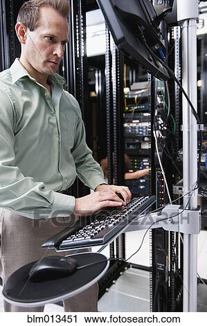 Stock Image - Caucasian businessman working in server room. Fotosearch