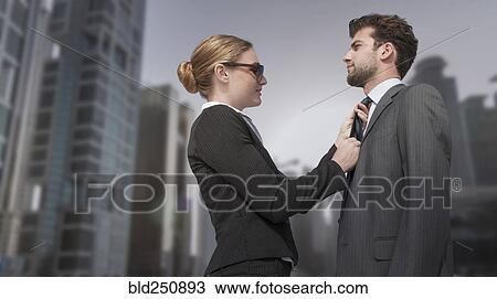 Stock Image - Caucasian businesswoman adjusting necktie for businessman. Fotosearch