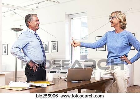 Caucasian businesswoman gesturing thumbs-up to businessman View Large Photo Image Stock Photograph - Caucasian businesswoman gesturing thumbs-up to businessman. Fotosearch