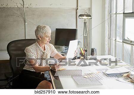 Caucasian businesswoman reading paperwork in office View Large Photo Image Stock Image - Caucasian businesswoman reading paperwork in office. Fotosearch