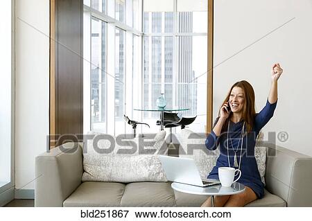Stock Photo - Caucasian businesswoman talking on cell phone and celebrating. Fotosearch