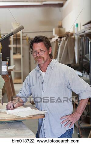 Stock Image - Caucasian carpenter in workshop. Fotosearch