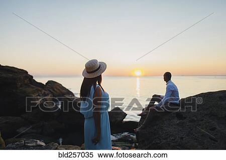 Stock Photography - Caucasian couple admiring scenic view of ocean sunset. Fotosearch