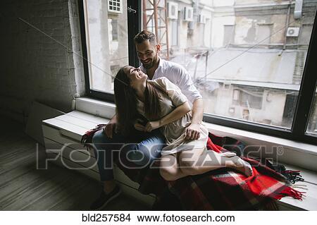 Caucasian couple cuddling on bench near window View Large Photo Image Picture - Caucasian couple cuddling on bench near window. Fotosearch