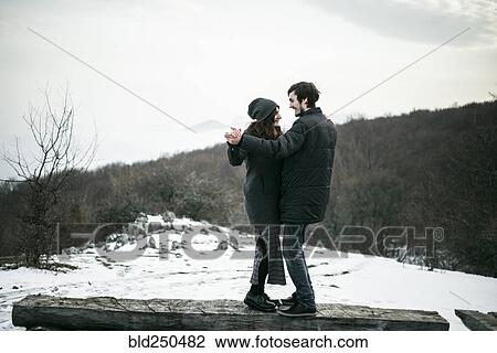 Stock Image - Caucasian couple dancing on log in winter. Fotosearch