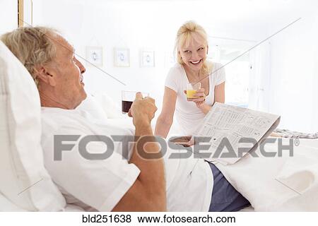 Stock Photo - Caucasian couple drinking coffee and juice in bed. Fotosearch