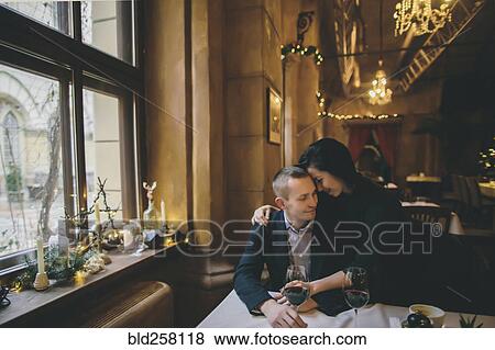 Stock Photo - Caucasian couple drinking wine and hugging in restaurant. Fotosearch
