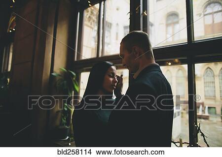 Picture - Caucasian couple embracing near window. Fotosearch