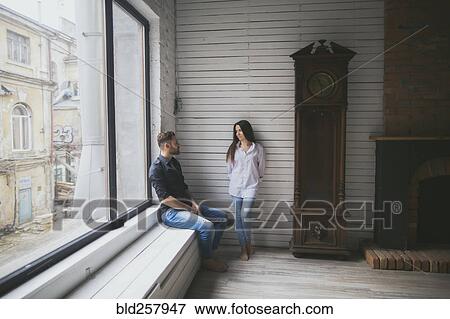 Caucasian couple hanging out near window View Large Photo Image Stock Photo - Caucasian couple hanging out near window. Fotosearch