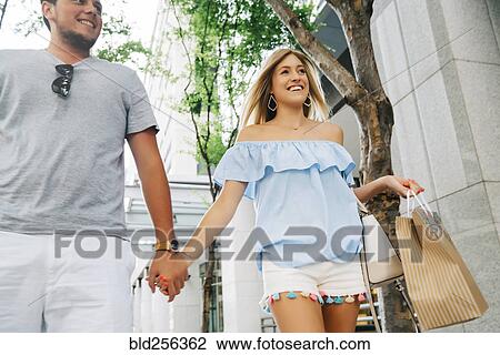 Caucasian couple holding hands carrying shopping bags in city View Large Photo Image Stock Image - Caucasian couple holding hands carrying shopping bags in city. Fotosearch