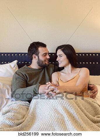 Caucasian couple holding hands in bed View Large Photo Image Stock Photo - Caucasian couple holding hands in bed. Fotosearch