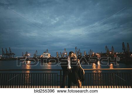 Stock Photograph - Caucasian couple hugging at waterfront. Fotosearch