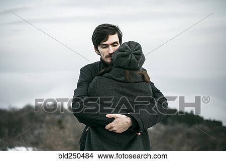 Picture - Caucasian couple hugging on hill. Fotosearch
