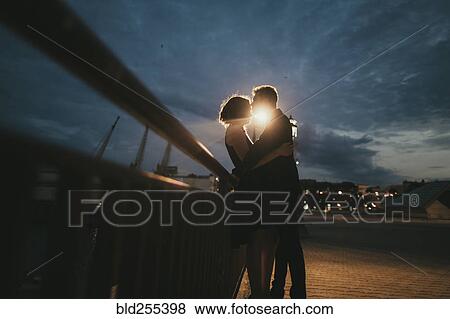 Caucasian couple kissing near railing at night View Large Photo Image Stock Photo - Caucasian couple kissing near railing at night. Fotosearch