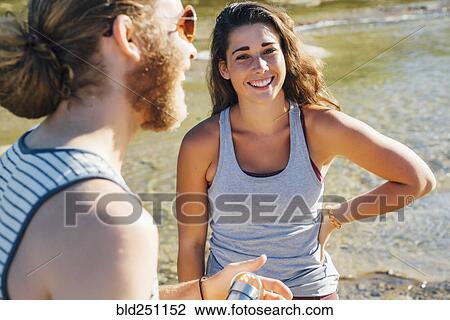 Stock Image - Caucasian couple laughing near river. Fotosearch