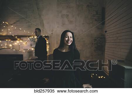 Stock Photography - Caucasian couple leaning on piano near fireplace. Fotosearch