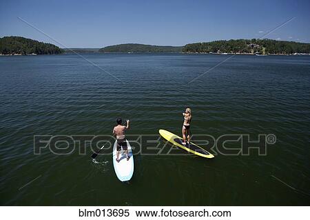 Caucasian couple on paddle boards on lake View Large Photo Image Stock Photography - Caucasian couple on paddle boards on lake. Fotosearch