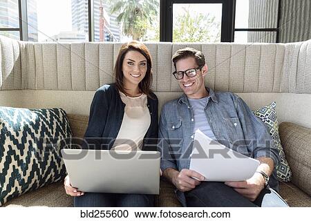 Caucasian couple on sofa holding laptop and paperwork View Large Photo Image Stock Image - Caucasian couple on sofa holding laptop and paperwork. Fotosearch