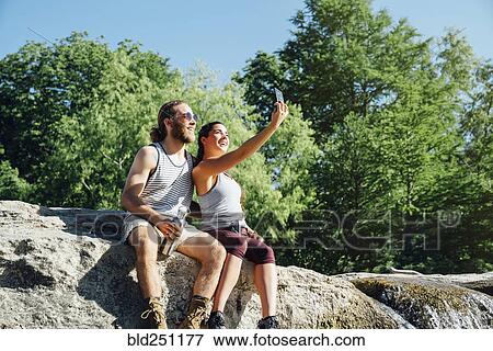 Caucasian couple posing for cell phone selfie on rocks View Large Photo Image Stock Photo - Caucasian couple posing for cell phone selfie on rocks. Fotosearch