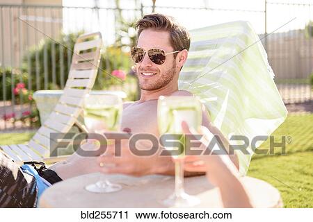Caucasian couple relaxing in lounge chairs holding drinks View Large Photo Image Stock Image - Caucasian couple relaxing in lounge chairs holding drinks. Fotosearch