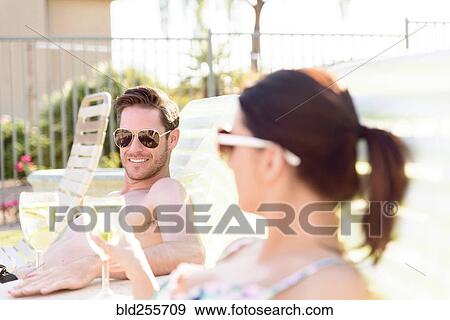Stock Photo - Caucasian couple relaxing in lounge chairs. Fotosearch
